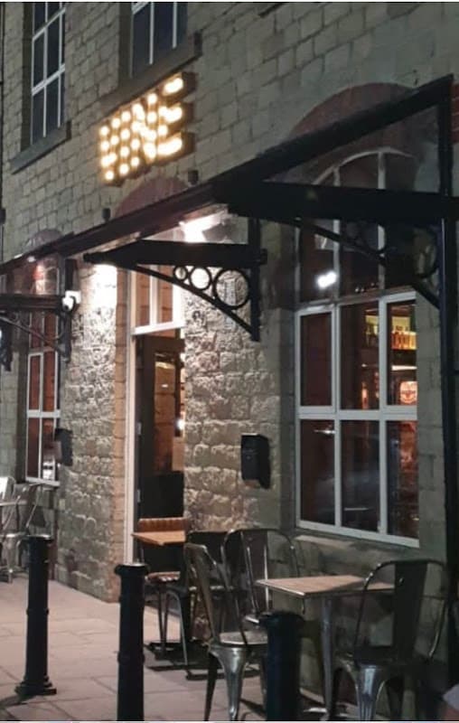 Vine Bar entrance with illuminated sign, outdoor seating, and stone facade in West Vale, Yorkshire.