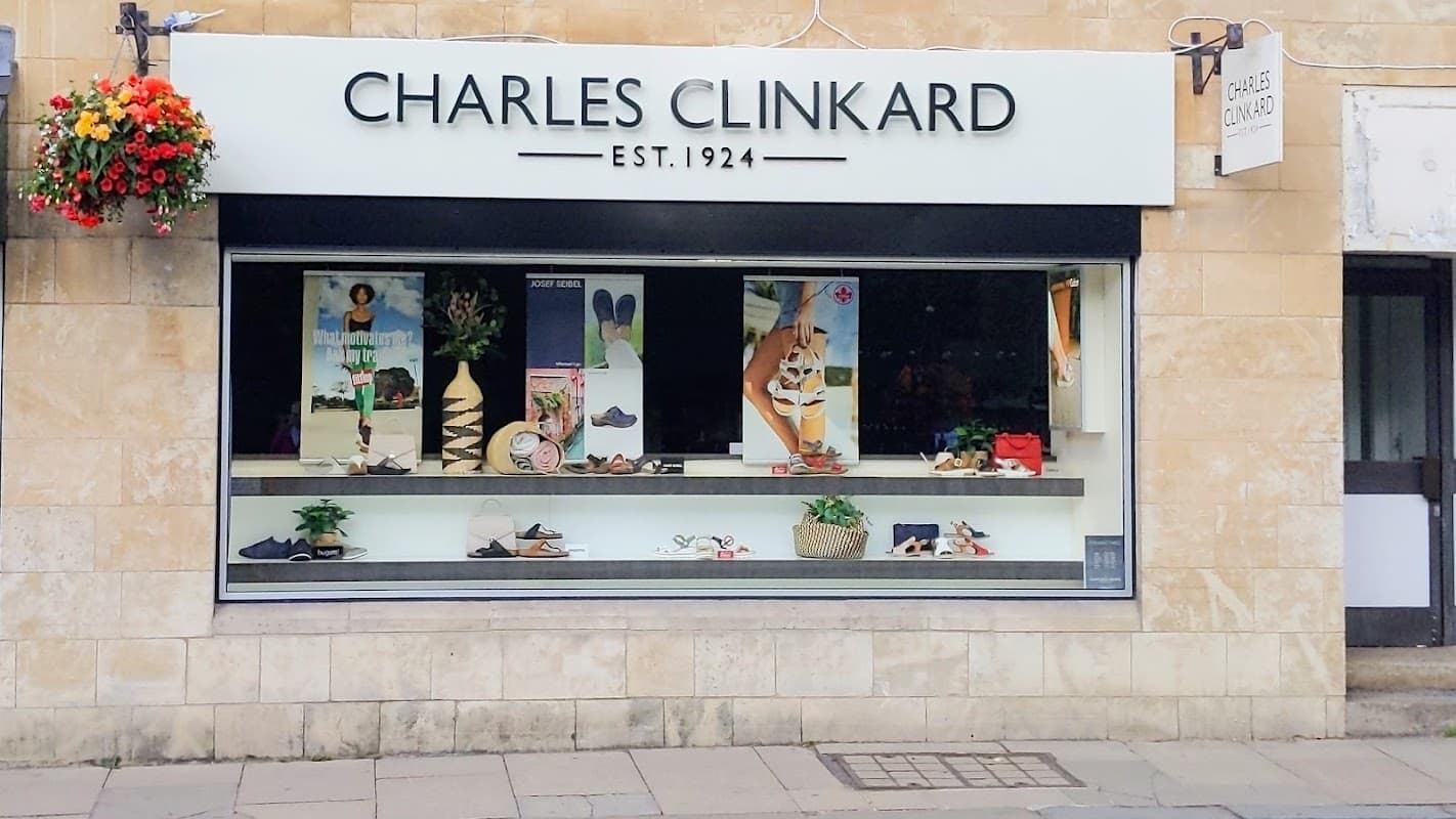 Shopfront of Charles Clinkard, featuring shoes and accessories, with floral decorations above the display window.