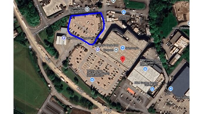 Pay & Display parking area in Whitby, Yorkshire, marked in blue, near shopping facilities and other parked cars.