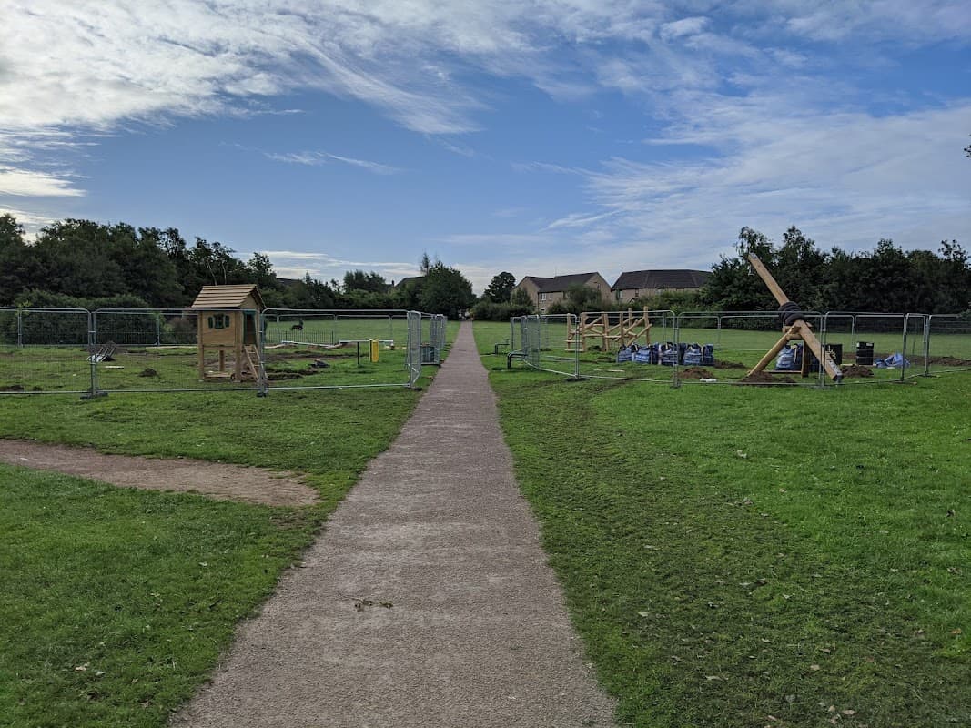 Pathway through Wickersley Park with construction barriers, grassy areas, and play equipment in the background.