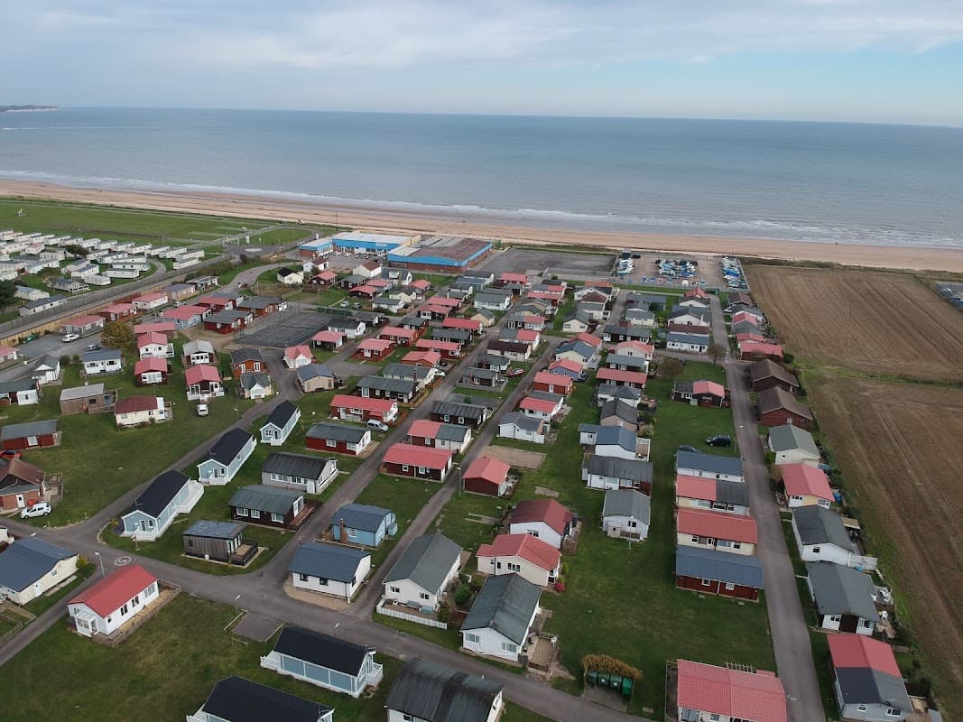 Aerial view of South Shore Holiday Village, featuring colorful chalets near the beach and a vast sea in the background.