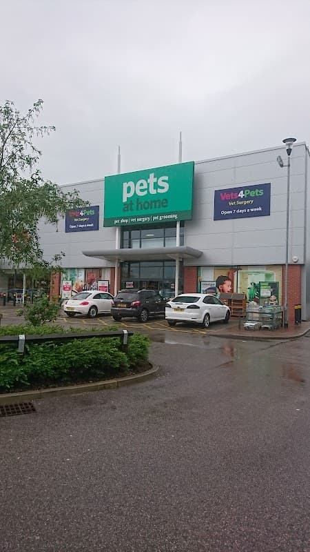 Pets at Home store with large green sign, cars parked outside, and promotional banners visible in a shopping park.