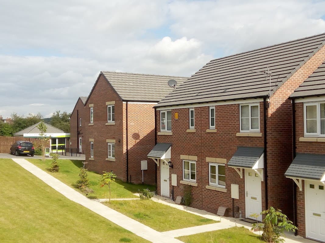 Modern brick houses with neatly trimmed lawns and a cloudy sky in Highfield Park, Wombwell, Yorkshire.