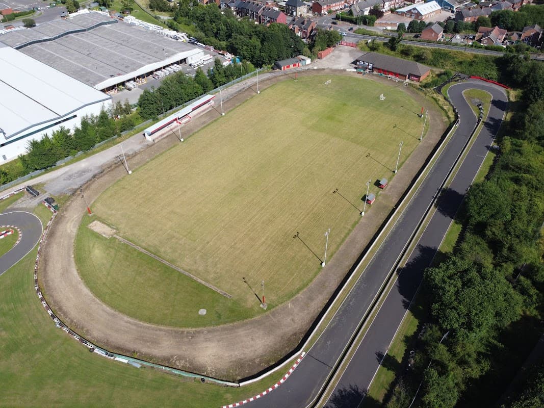 Aerial view of Wombwell Town FC's football pitch, surrounded by trees and nearby buildings in Wombwell, Yorkshire.
