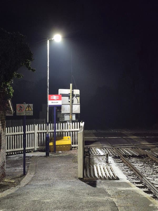 Wressle bus stop at night, featuring a lit platform, railway tracks, and surrounding dark, foggy atmosphere.