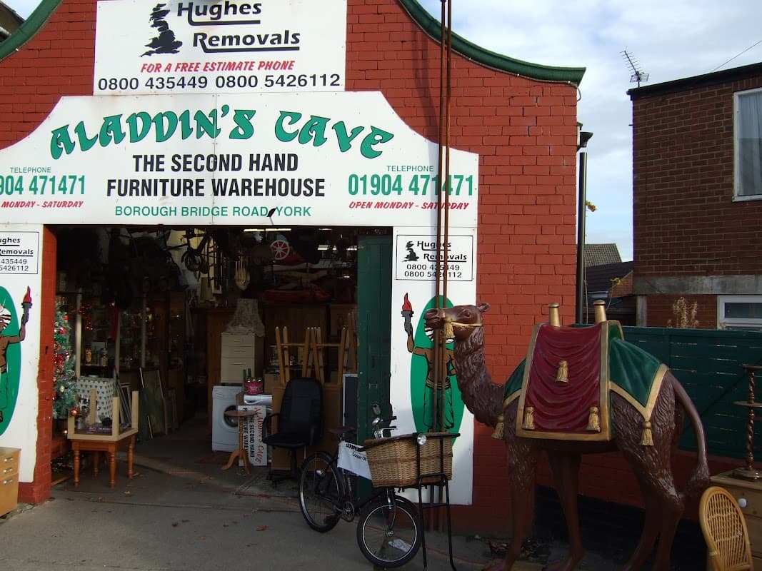Colorful storefront with "Aladdin's Cave" sign, a camel statue, and a bicycle at the entrance in York.