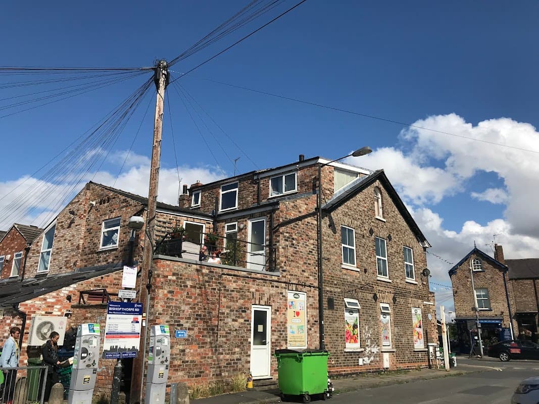 Bishopthorpe Road Car Park with brick buildings, parking meters, and clear blue sky with scattered clouds.
