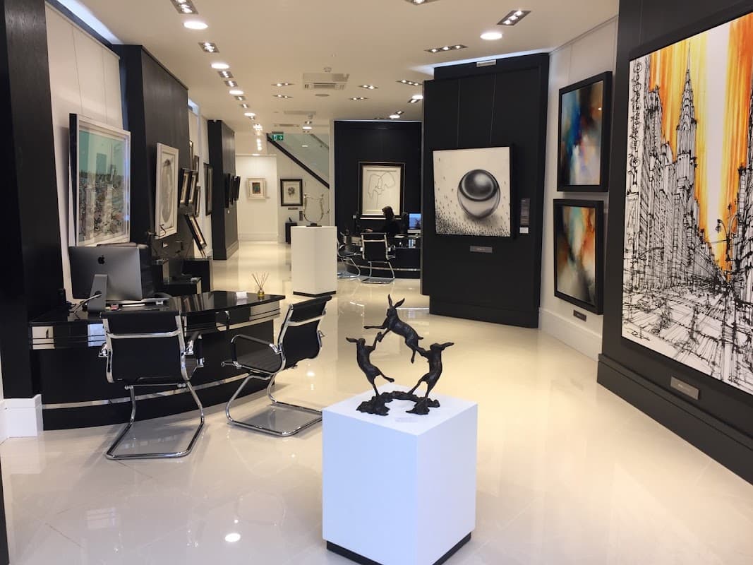 Modern art gallery with sleek black and white decor, featuring sculptures and various framed artworks on display.