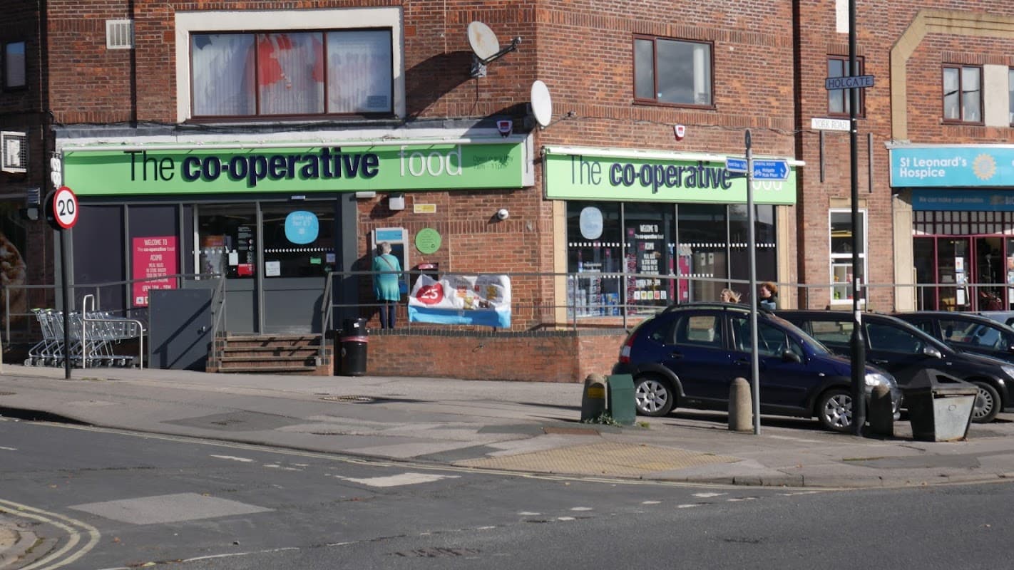Co-op Food store in Acomb with green signage, shopping trolleys outside, and nearby street signs and buildings.