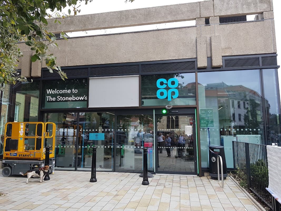 Co-op Food storefront at The Stonebow, featuring glass entrance, signage, and a nearby construction lift.