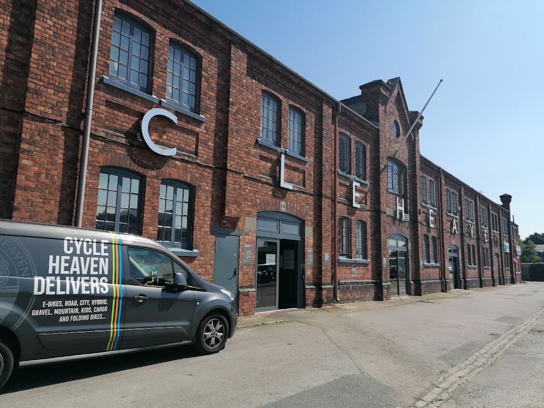 Brick building with large letters spelling "CYCLE HEAVEN," featuring a delivery van parked outside.