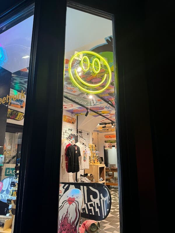 Neon smiley face sign illuminates the window of Easy Street sports shop, showcasing vibrant interior and merchandise.