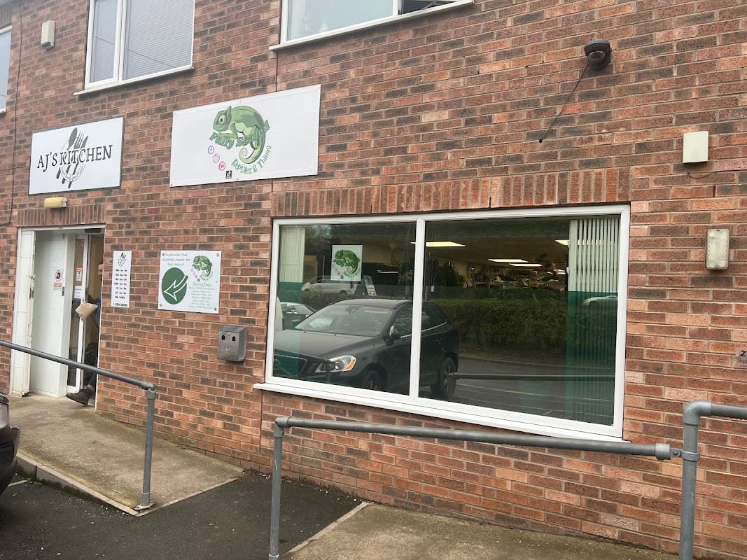 Brick exterior of a pet shop with large windows, signage featuring a chameleon, and a ramp for accessibility.