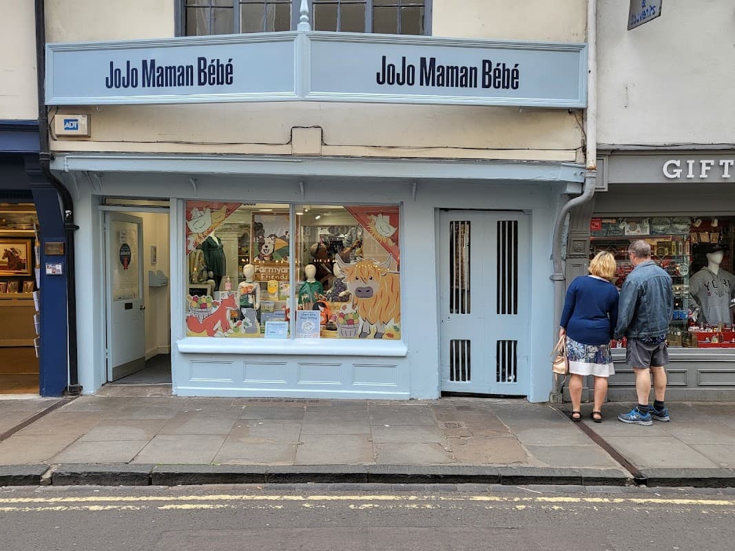 Colorful storefront with playful window display, featuring children's clothing and accessories, in a charming street setting.