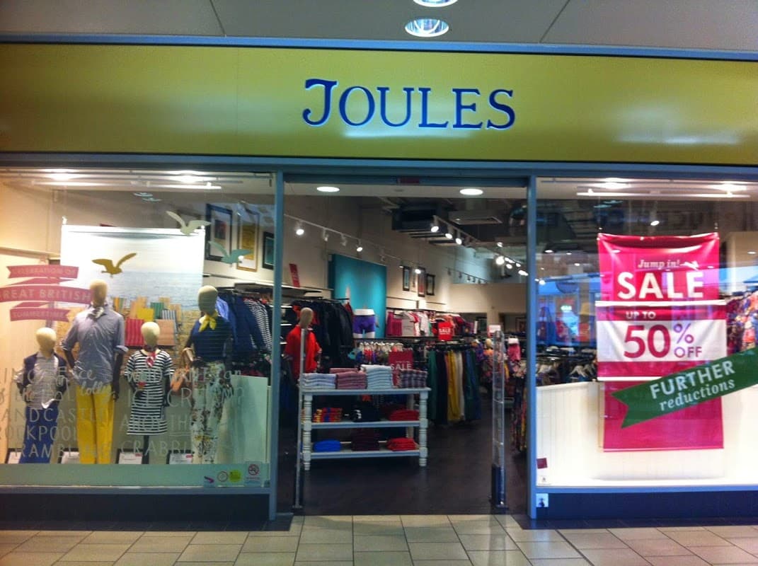 Bright storefront of Joules Outlet featuring clothing displays, mannequins, and a large sale banner.