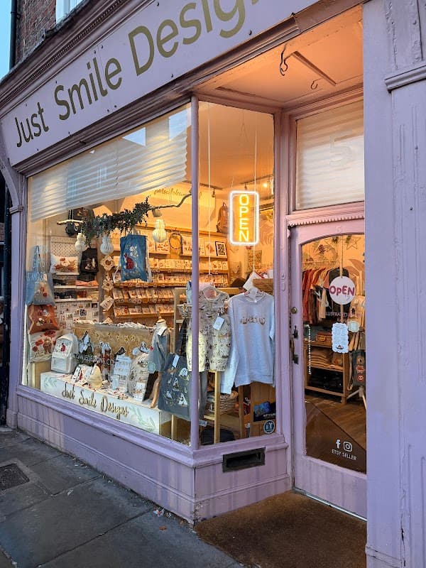 Brightly lit gift shop window featuring various items, including clothing and accessories, with an "OPEN" sign.