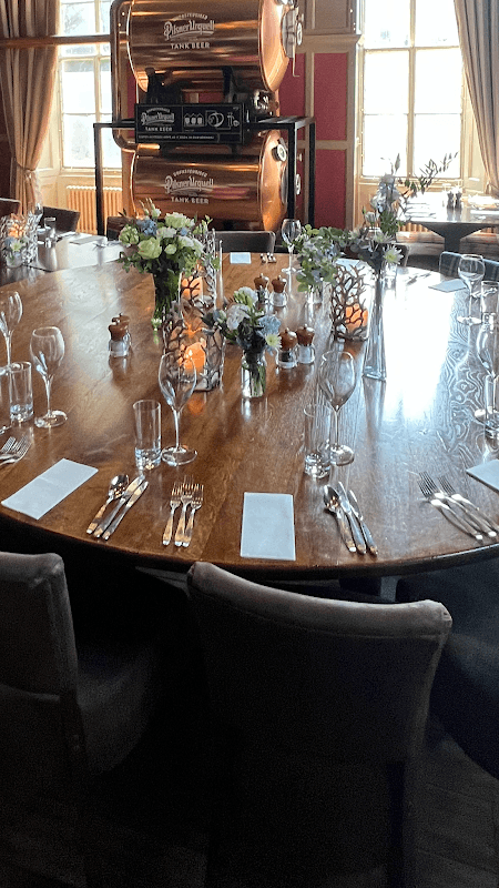 Elegant dining table set with floral arrangements, glassware, and candles, surrounded by cozy seating in a warm venue.