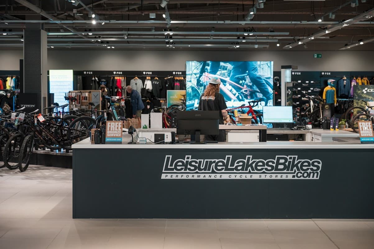 Modern bike shop interior featuring a service counter, bikes on display, and cycling apparel in the background.