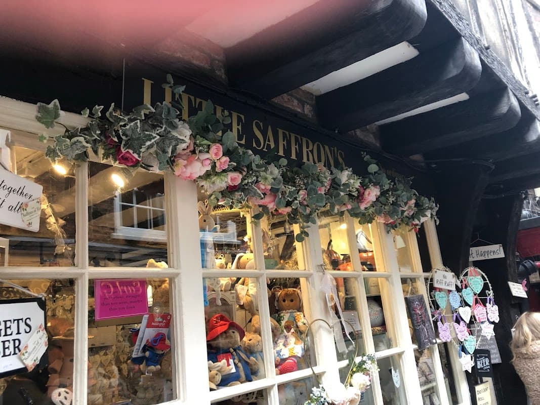 Charming gift shop entrance with floral decor, teddy bears, and colorful signs in York, Yorkshire.