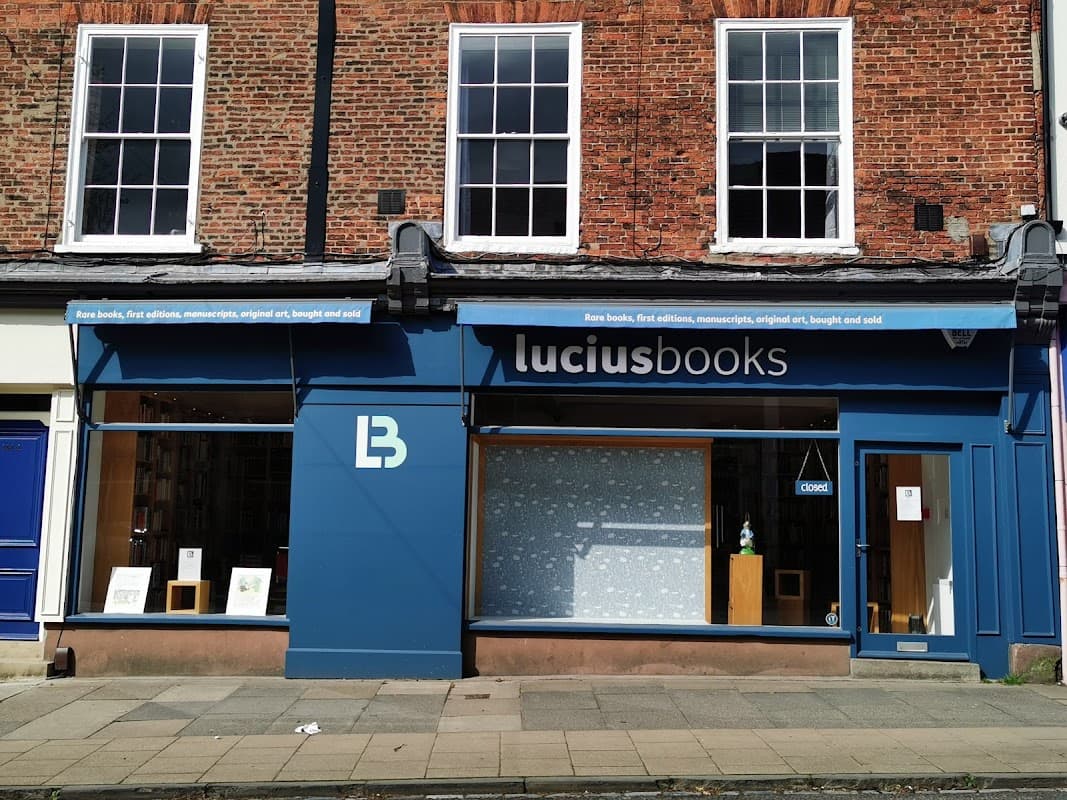 Charming bookshop exterior with large windows, blue signage, and a display of rare books in York, Yorkshire.