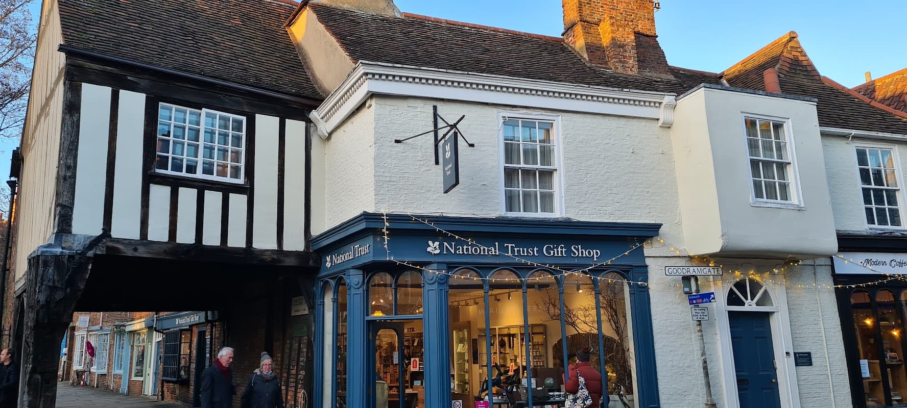 National Trust Gift Shop with blue signage, displaying various items, in a historic building in York, Yorkshire.