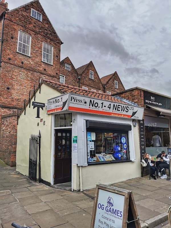 Quaint bookshop "No 1 4 News" with a colorful window display, surrounded by historic brick buildings in York.