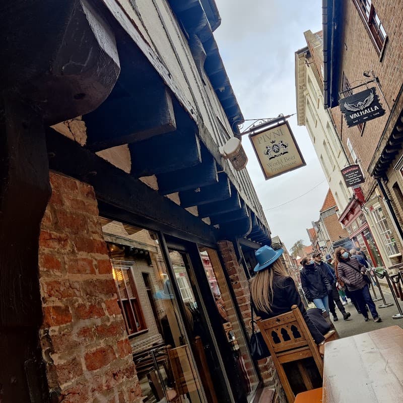 Historic pub with a wooden sign, brick exterior, and patrons walking on a cobblestone street in York, Yorkshire.