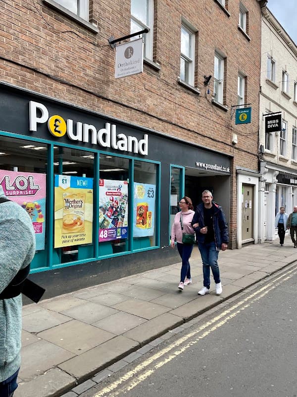 Poundland storefront with colorful signage; two people walking by on a city street in York, Yorkshire.