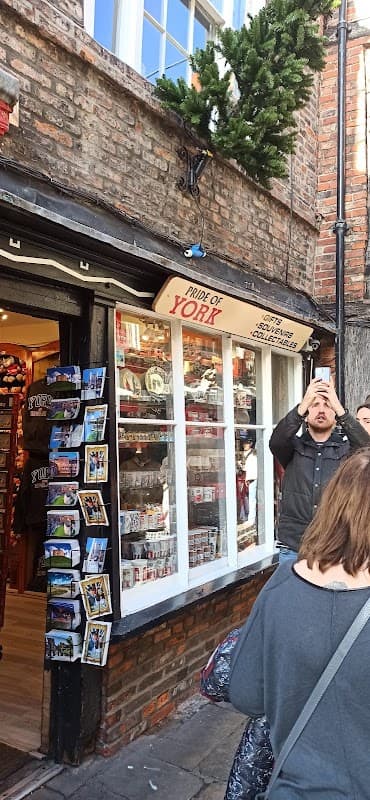 Charming gift shop with "Pride of York" sign, displaying souvenirs and postcards, surrounded by historic brick architecture.