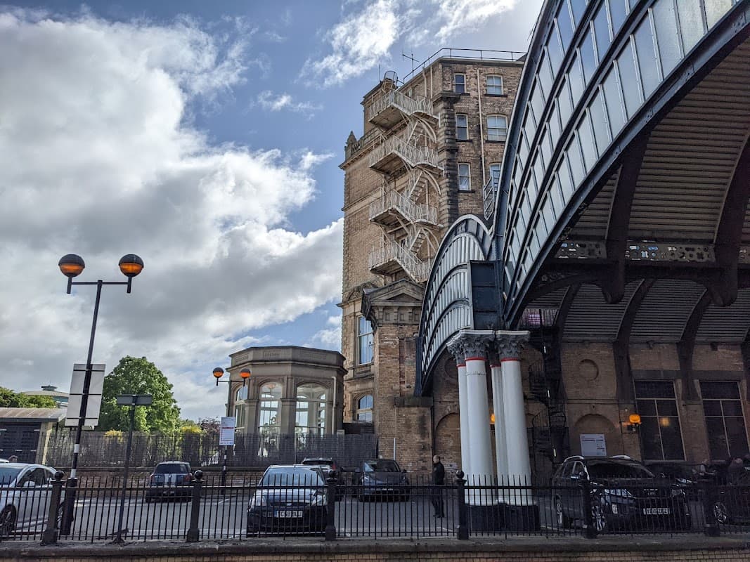 Priory Street Car Park features a historic building, a modern overpass, and parked cars under a partly cloudy sky.