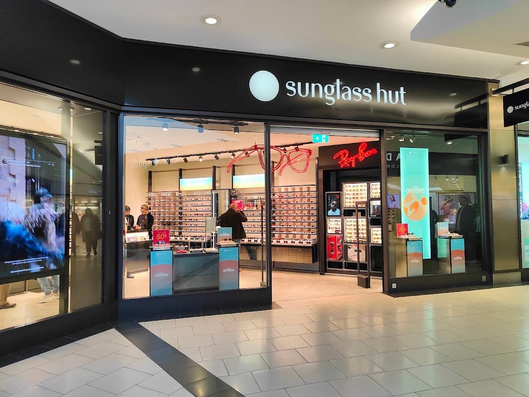 Sunglass Hut storefront featuring a variety of sunglasses and a promotional display inside a shopping center.
