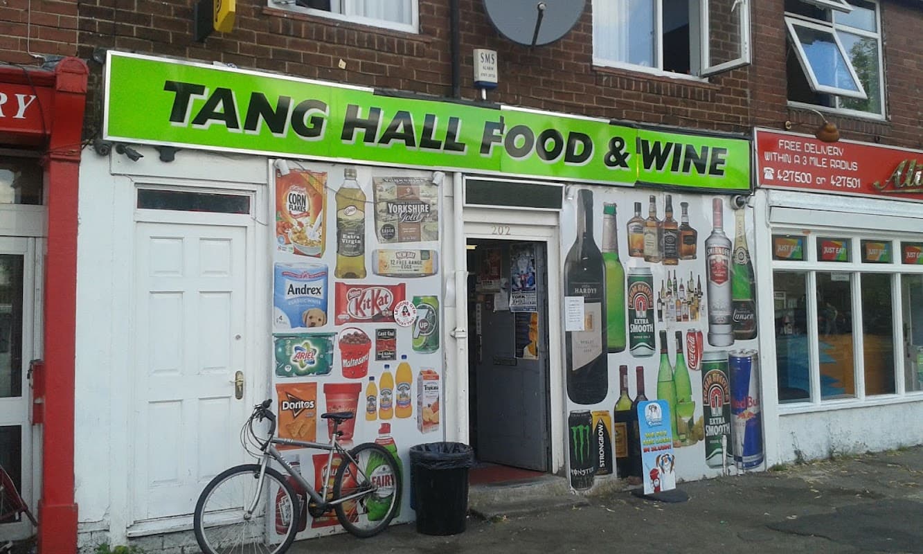 Bright storefront with "TANG HALL FOOD & WINE" sign, featuring beverage advertisements and a bicycle parked outside.
