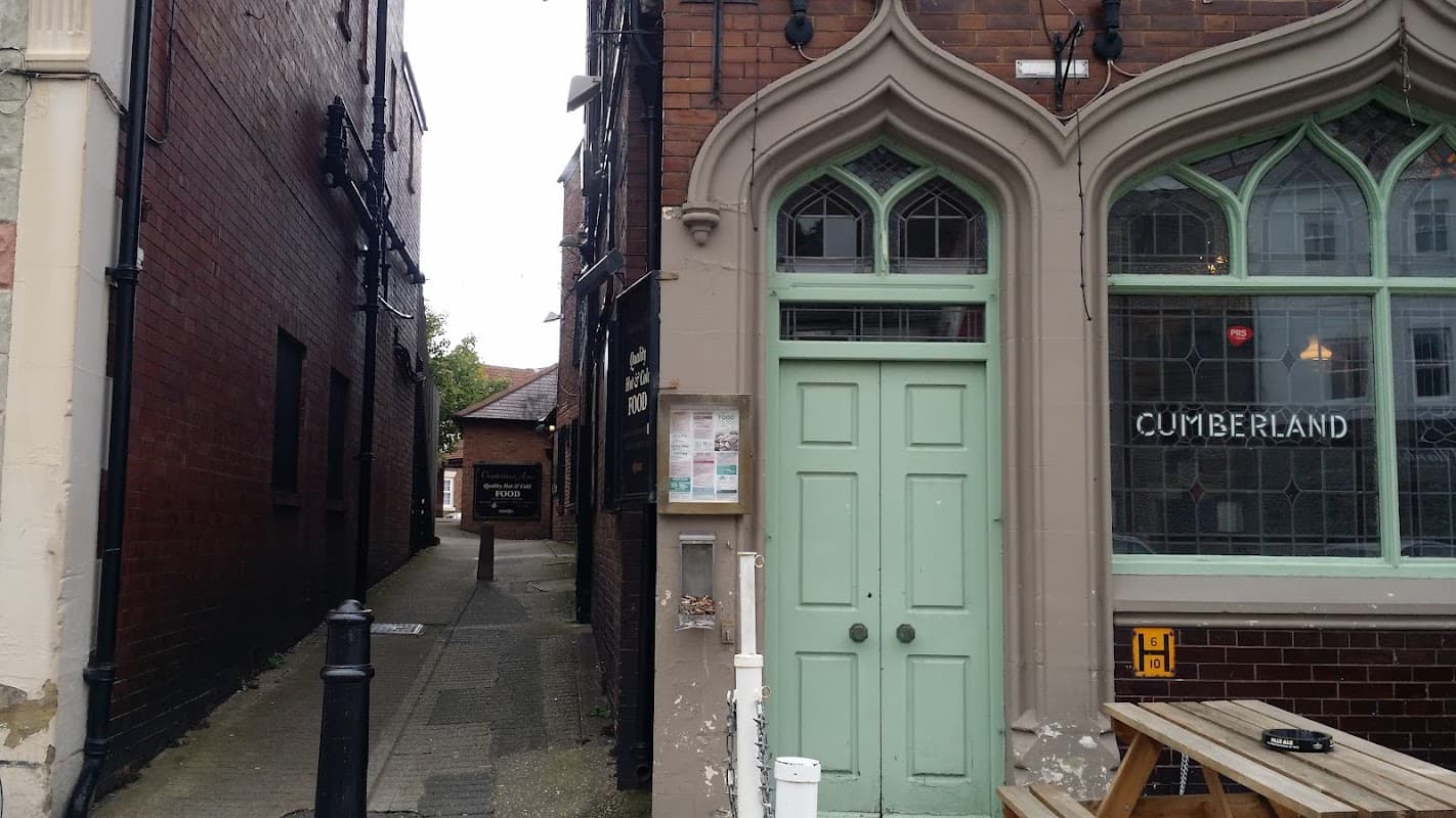 Historic pub with green doors, arched windows, and a narrow alleyway beside it in York, Yorkshire.