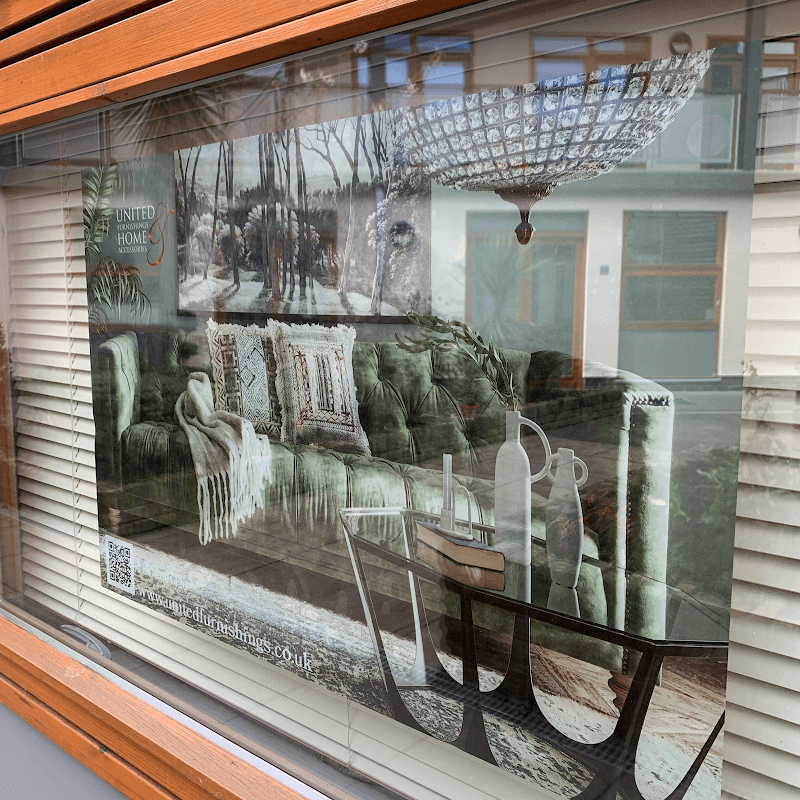 A stylish display featuring a green sofa, decorative pillows, and a chandelier in a window setting.