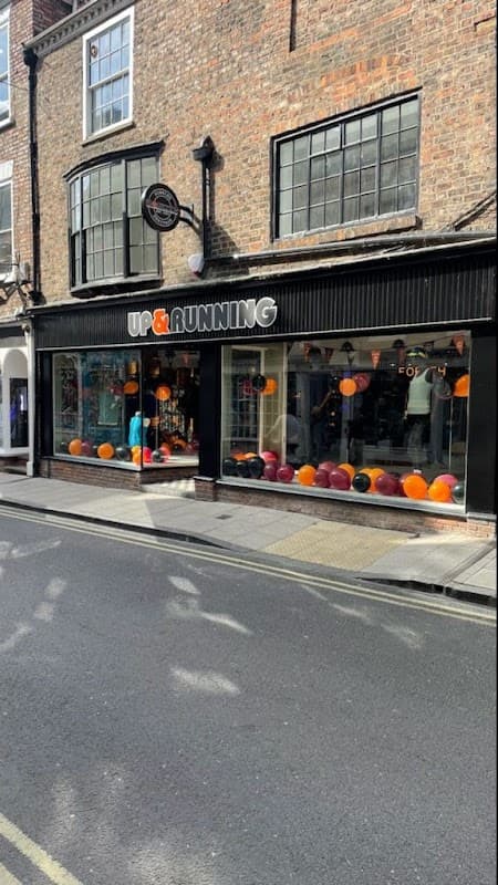 Sports shop storefront with large windows displaying colorful balloons and athletic gear in York, Yorkshire.