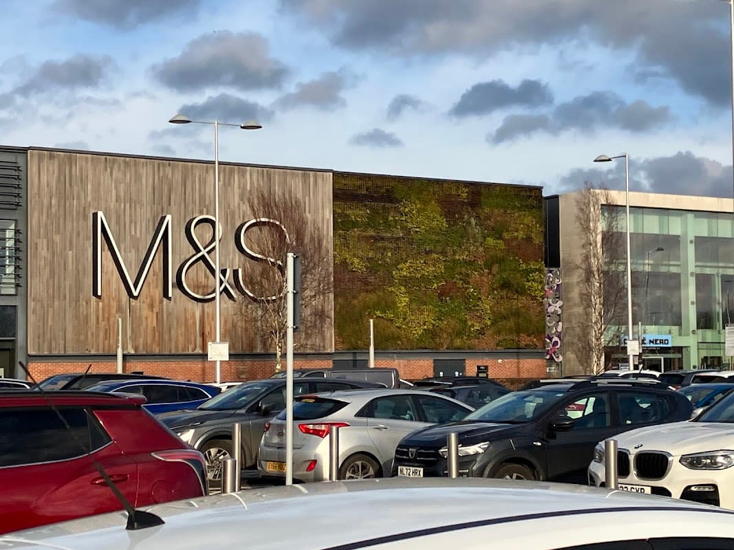 M&S store with a green wall, surrounded by parked cars and a cloudy sky at Vangarde Shopping Park, York.