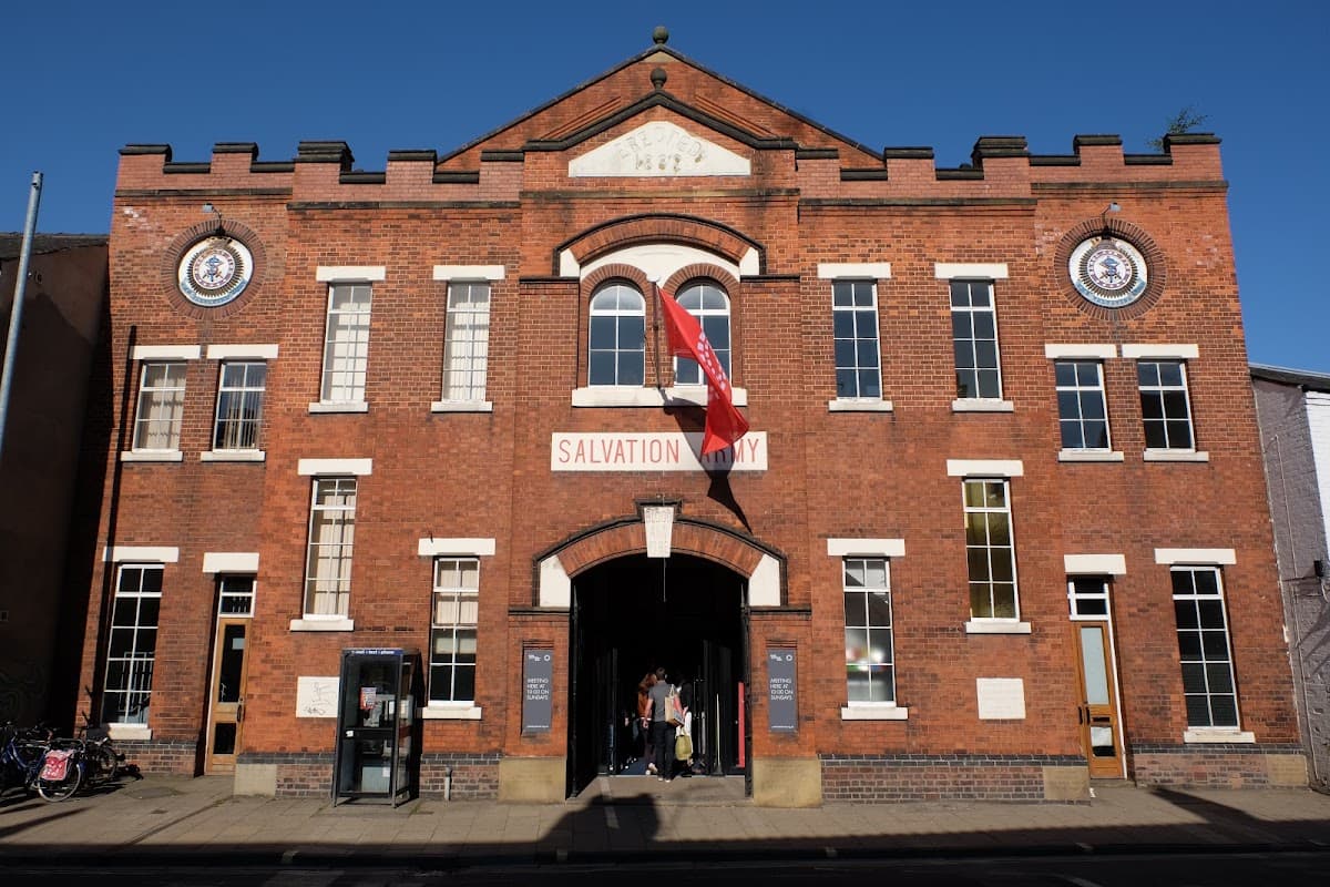 Historic brick building with arched windows, a flag, and signage for the Salvation Army in York. Clear blue sky above.