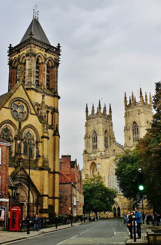 York Oratory stands alongside York Minster, featuring intricate architecture and a cloudy sky above.