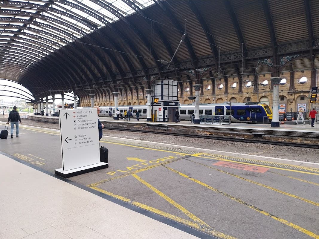 York Railway Station features a spacious platform, signage for directions, and parked trains under a vaulted roof.