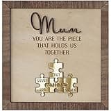 Wooden frame with engraved "Mum" text, featuring gold puzzle pieces labeled "Mum," "Dad," and "Sarah."