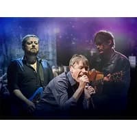 Three men performing on stage, one singing into a microphone, another playing guitar, and the third with a blue guitar.