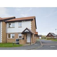 Two-story brick and white stucco cottage with red-tiled roof, small front porch, and adjacent driveway.
