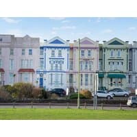 Colorful row of Victorian-style townhouses with ornate details, featuring pastel hues and decorative trim.