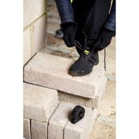 Amblers Safety black boot with side zip, composite toe, and lace-up front, worn by person on concrete blocks.