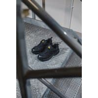 Black Amblers Safety vegan-friendly shoes, size 5, with yellow logo on tongue, resting on metal stairs.