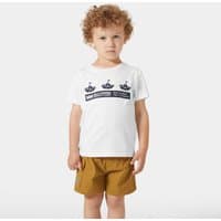 White Helly Hansen kids' T-shirt with navy graphic design, worn by a child with curly hair, paired with brown shorts.