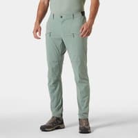 Green Helly Hansen men's trousers with zippered pockets, belt loops, and tapered fit, worn by a model with hiking boots.