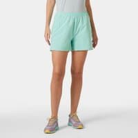 Green Helly Hansen women's shorts, elastic waistband, knee-length, lightweight fabric, worn by a model with sneakers.