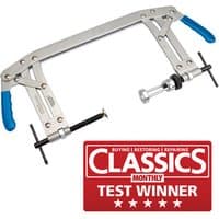 Universal valve spring compressor with silver metal frame, blue rubber grips, and adjustable clamps.