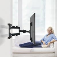 Black Hama TV mount for 65" screens, adjustable arm, wall-mounted, holding a flat screen in a modern living room.